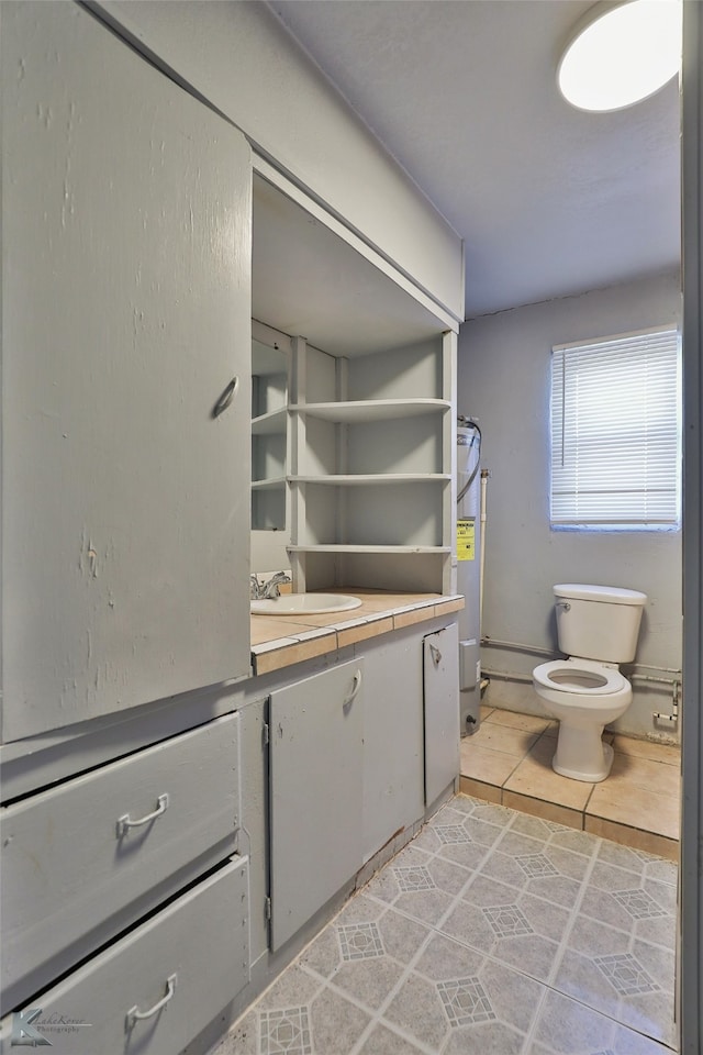 bathroom with tile patterned flooring, water heater, vanity, and toilet