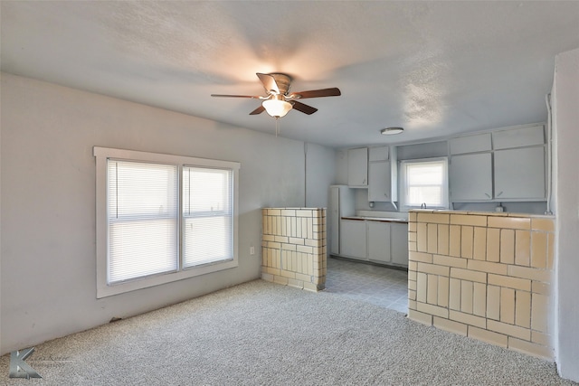 kitchen featuring a textured ceiling, light carpet, and ceiling fan