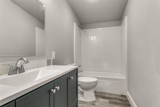 full bathroom featuring vanity, wood finished floors, bathing tub / shower combination, toilet, and a textured wall