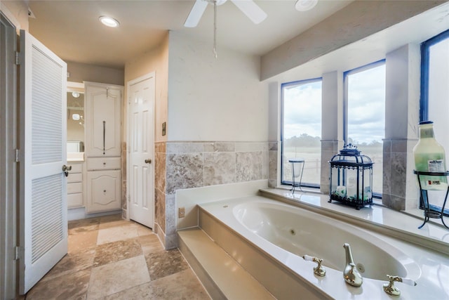 bathroom featuring a tub, tile walls, ceiling fan, and vanity