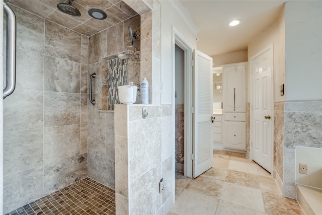 bathroom with a shower with shower door, vanity, and tile walls