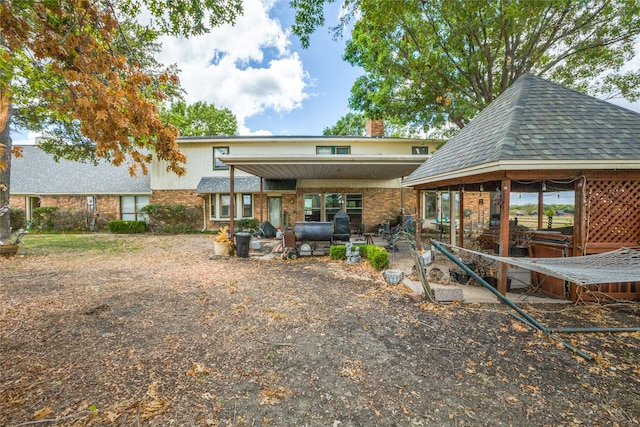 rear view of property featuring a patio and a gazebo