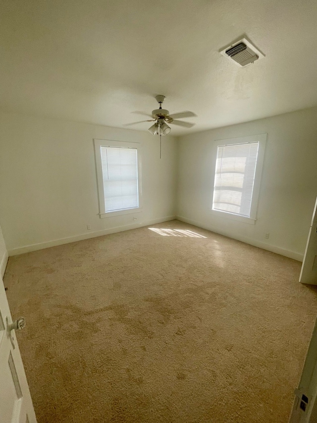 carpeted empty room featuring a wealth of natural light and ceiling fan