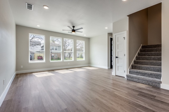 unfurnished living room with wood-type flooring, ceiling fan, and plenty of natural light