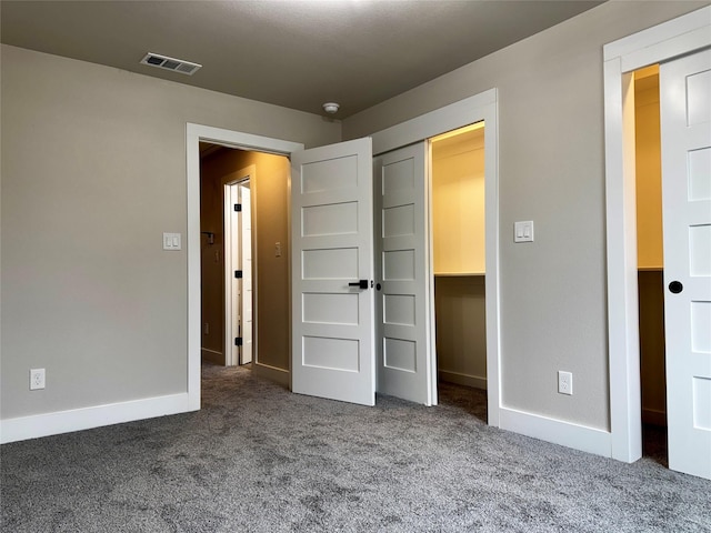 unfurnished bedroom featuring a closet, a spacious closet, and carpet