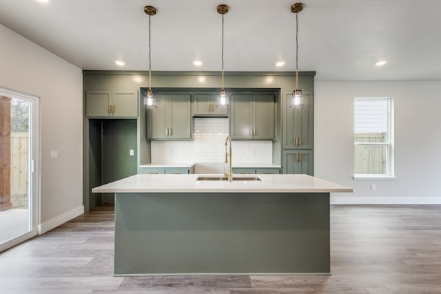 kitchen featuring pendant lighting, a center island with sink, light wood-type flooring, and sink