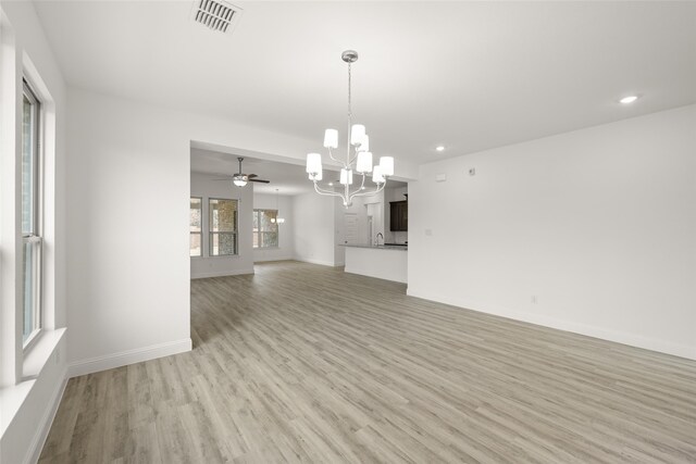 kitchen featuring appliances with stainless steel finishes, white cabinetry, light stone countertops, light wood-type flooring, and a kitchen island with sink