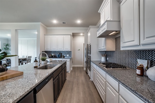 kitchen with ornamental molding, sink, light hardwood / wood-style flooring, white cabinetry, and stainless steel appliances