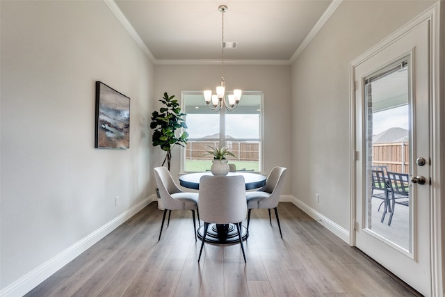 dining room featuring ornamental molding, light hardwood / wood-style flooring, a chandelier, and a wealth of natural light