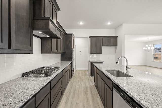 kitchen with sink, light stone counters, light wood-type flooring, stainless steel appliances, and decorative backsplash