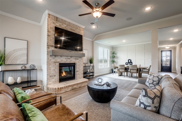 living room with plenty of natural light, ornamental molding, ceiling fan, and a brick fireplace