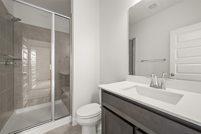 bathroom featuring tile patterned floors, toilet, a shower with shower door, and vanity