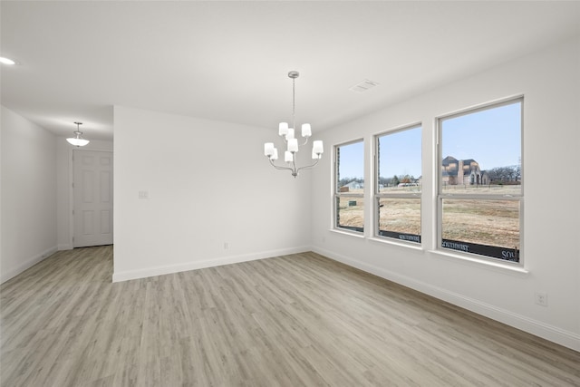 unfurnished room featuring a notable chandelier and light wood-type flooring