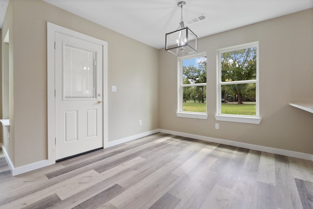 empty room featuring light hardwood / wood-style flooring and a chandelier