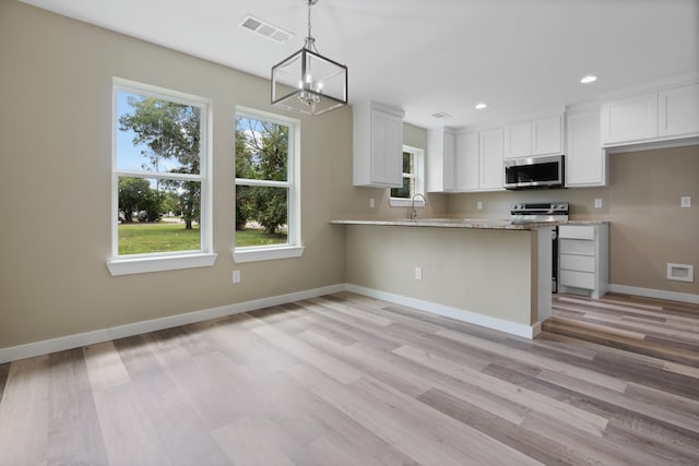 kitchen featuring pendant lighting, stainless steel appliances, white cabinetry, and light wood-type flooring