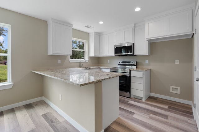 kitchen featuring appliances with stainless steel finishes, a healthy amount of sunlight, and white cabinetry