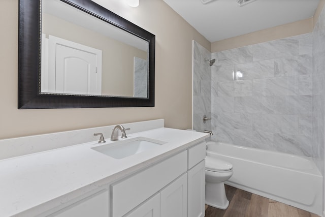 full bathroom with wood-type flooring, tiled shower / bath combo, vanity, and toilet