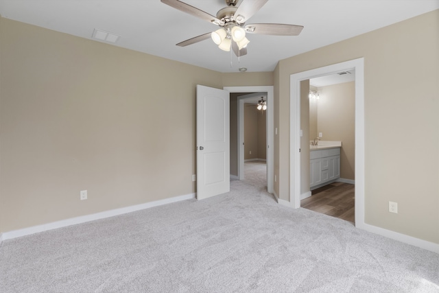 unfurnished bedroom featuring connected bathroom, sink, ceiling fan, and light colored carpet