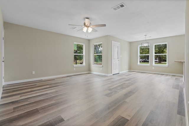 unfurnished living room featuring ceiling fan with notable chandelier and hardwood / wood-style floors