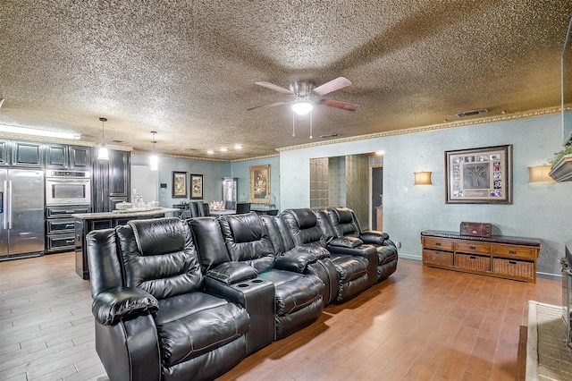 home theater room with a textured ceiling, light hardwood / wood-style flooring, and ceiling fan