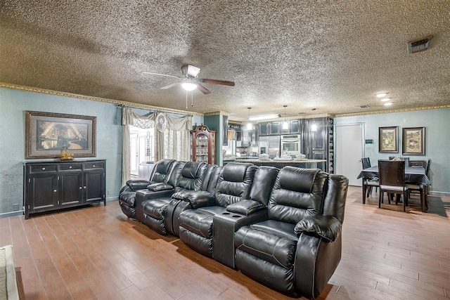 home theater featuring a textured ceiling, ceiling fan, and light hardwood / wood-style floors