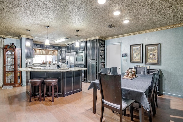 dining room with a textured ceiling, ornamental molding, sink, and light hardwood / wood-style floors