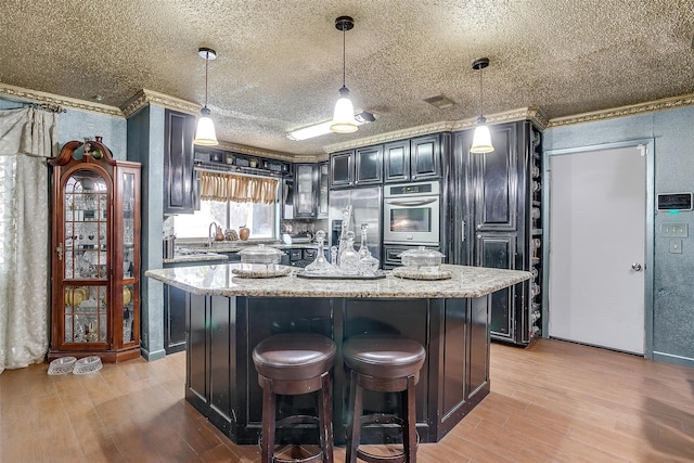 kitchen with hanging light fixtures, a kitchen island, light hardwood / wood-style floors, and crown molding