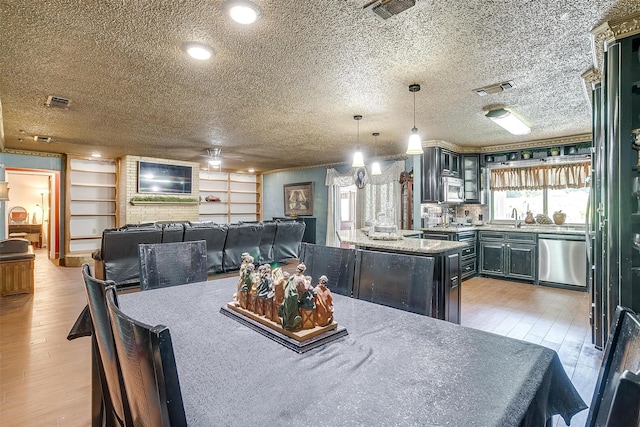 dining area with light wood-type flooring, ceiling fan, a textured ceiling, and sink