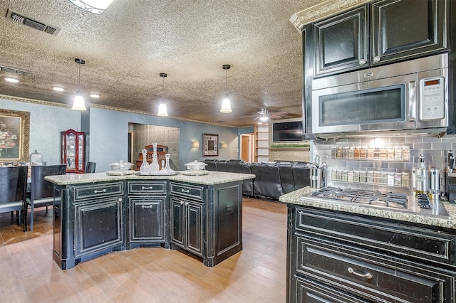 kitchen featuring a center island, stainless steel appliances, decorative light fixtures, and light hardwood / wood-style floors