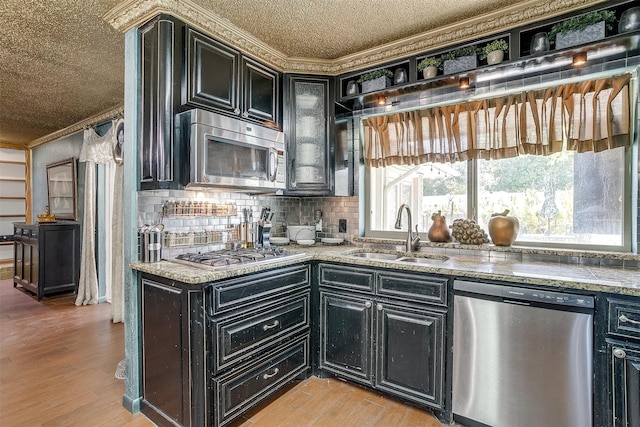 kitchen with crown molding, light hardwood / wood-style flooring, sink, light stone countertops, and appliances with stainless steel finishes