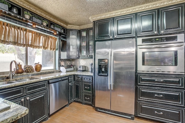 kitchen featuring light wood-type flooring, stainless steel appliances, stone countertops, and sink