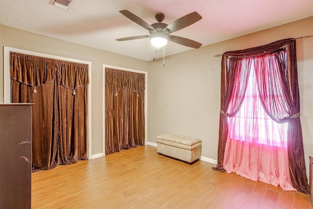 spare room featuring ceiling fan, wood-type flooring, and a textured ceiling