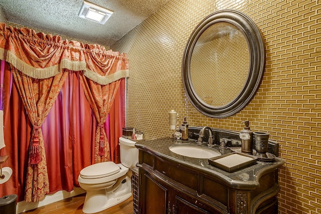 bathroom featuring hardwood / wood-style floors, walk in shower, toilet, brick wall, and vanity