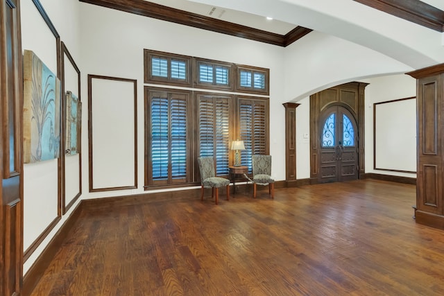 entrance foyer with crown molding, a towering ceiling, dark wood-type flooring, and decorative columns