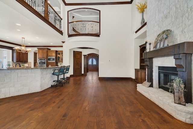 living room featuring a fireplace, dark hardwood / wood-style flooring, a towering ceiling, and ornamental molding