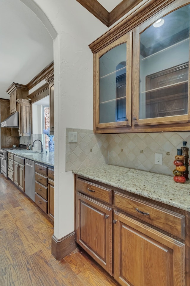 kitchen with light stone counters, tasteful backsplash, appliances with stainless steel finishes, and light hardwood / wood-style flooring