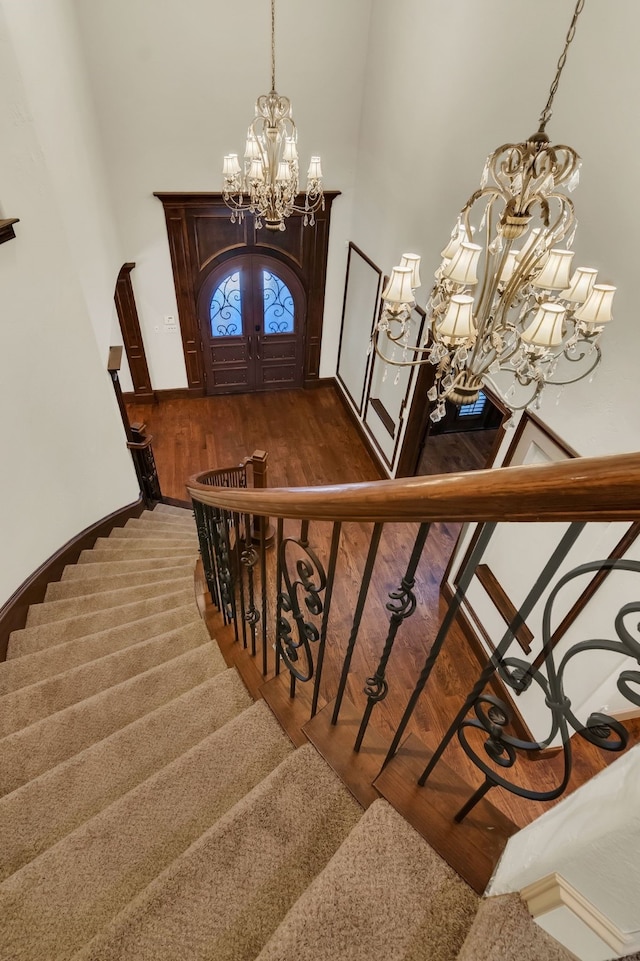 staircase with french doors, hardwood / wood-style flooring, and a notable chandelier