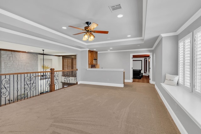 spare room with a tray ceiling, light carpet, crown molding, and ceiling fan