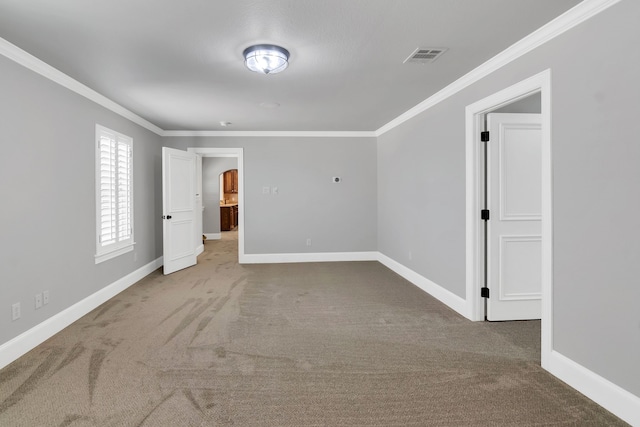 carpeted spare room featuring crown molding