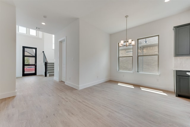 unfurnished dining area with light wood-type flooring and a chandelier