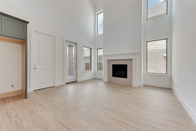 unfurnished living room with a towering ceiling and light hardwood / wood-style floors