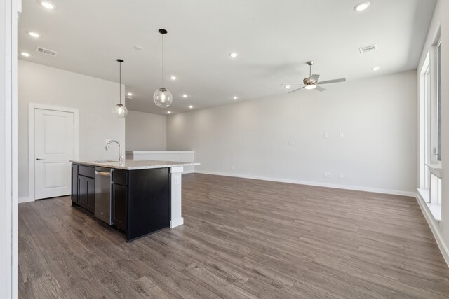 kitchen with light wood-type flooring, pendant lighting, white cabinetry, an island with sink, and sink