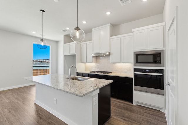 kitchen with stainless steel appliances, backsplash, dark wood-type flooring, a sink, and under cabinet range hood