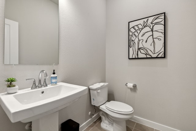 bathroom with toilet, sink, and tile patterned floors