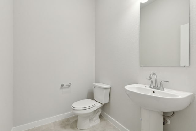 bathroom with tile patterned flooring, baseboards, a sink, and toilet