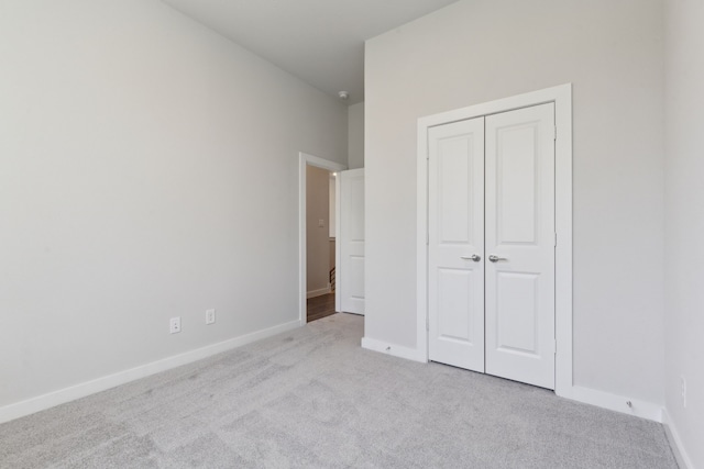 unfurnished bedroom with carpet, a closet, and baseboards