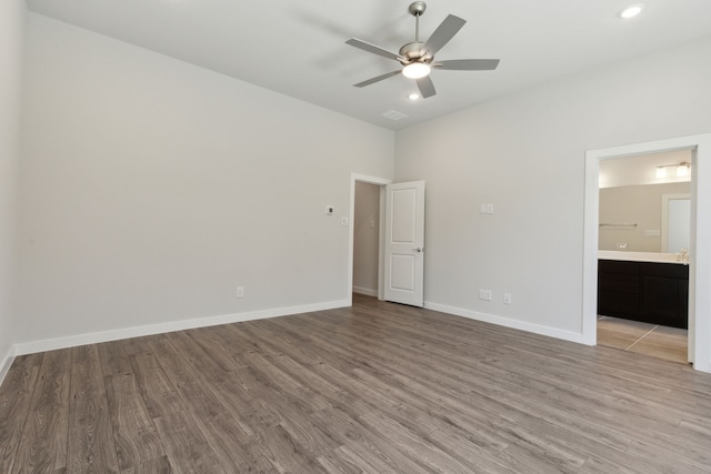 unfurnished bedroom with ensuite bath, light wood-style flooring, baseboards, and a ceiling fan