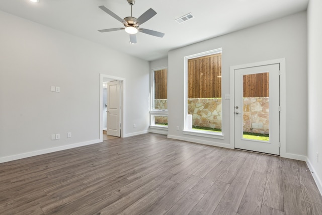 empty room featuring baseboards, visible vents, ceiling fan, and wood finished floors