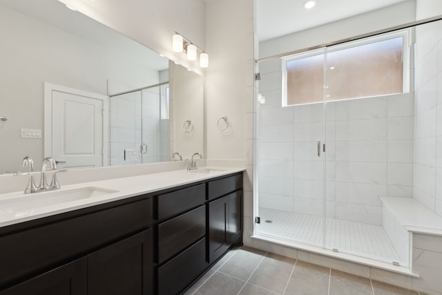 full bath featuring double vanity, a stall shower, a sink, and tile patterned floors