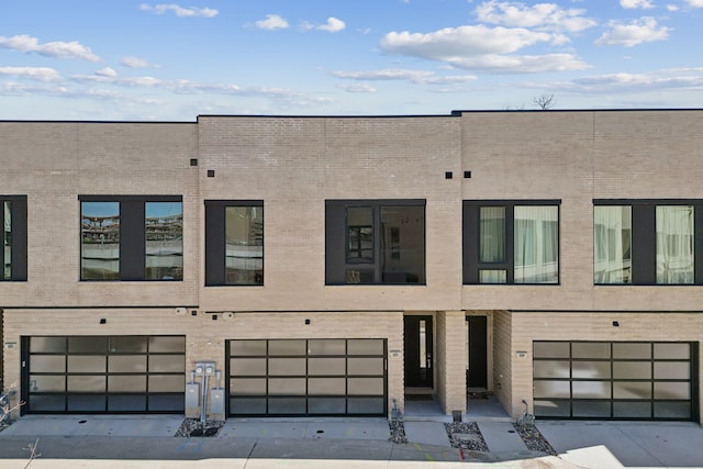 view of front of home with concrete driveway, brick siding, and an attached garage